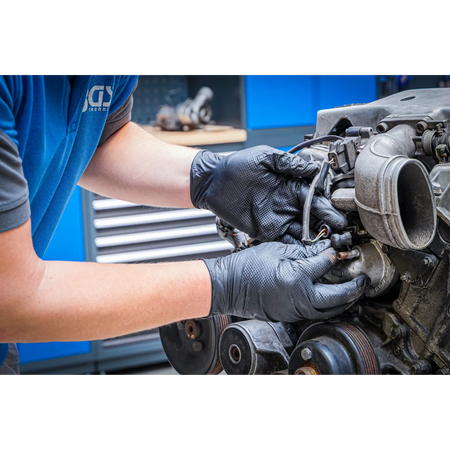 Bild der Nutzung von Einweghandschuhen an einem ausgebauten Motor in der Kfz-Werkstatt